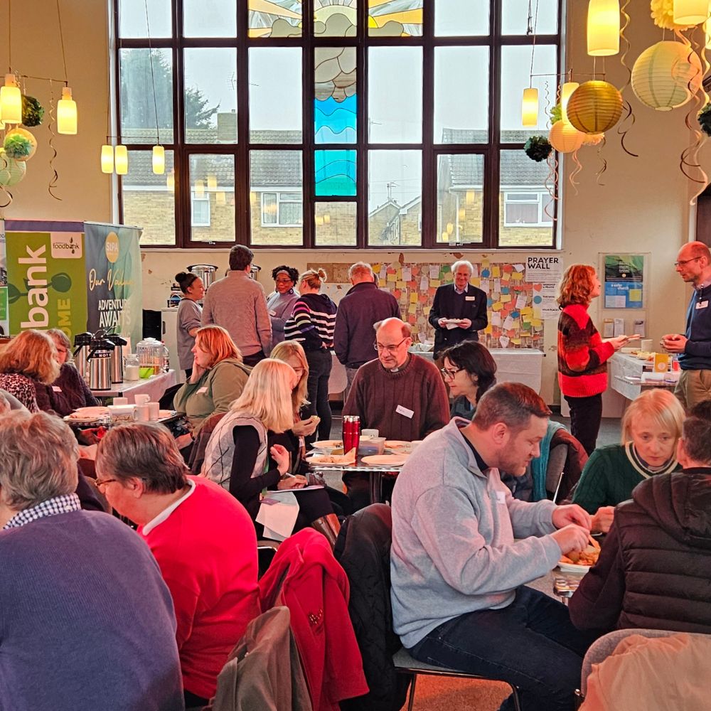 People gather in small groups at tables in a colourful room